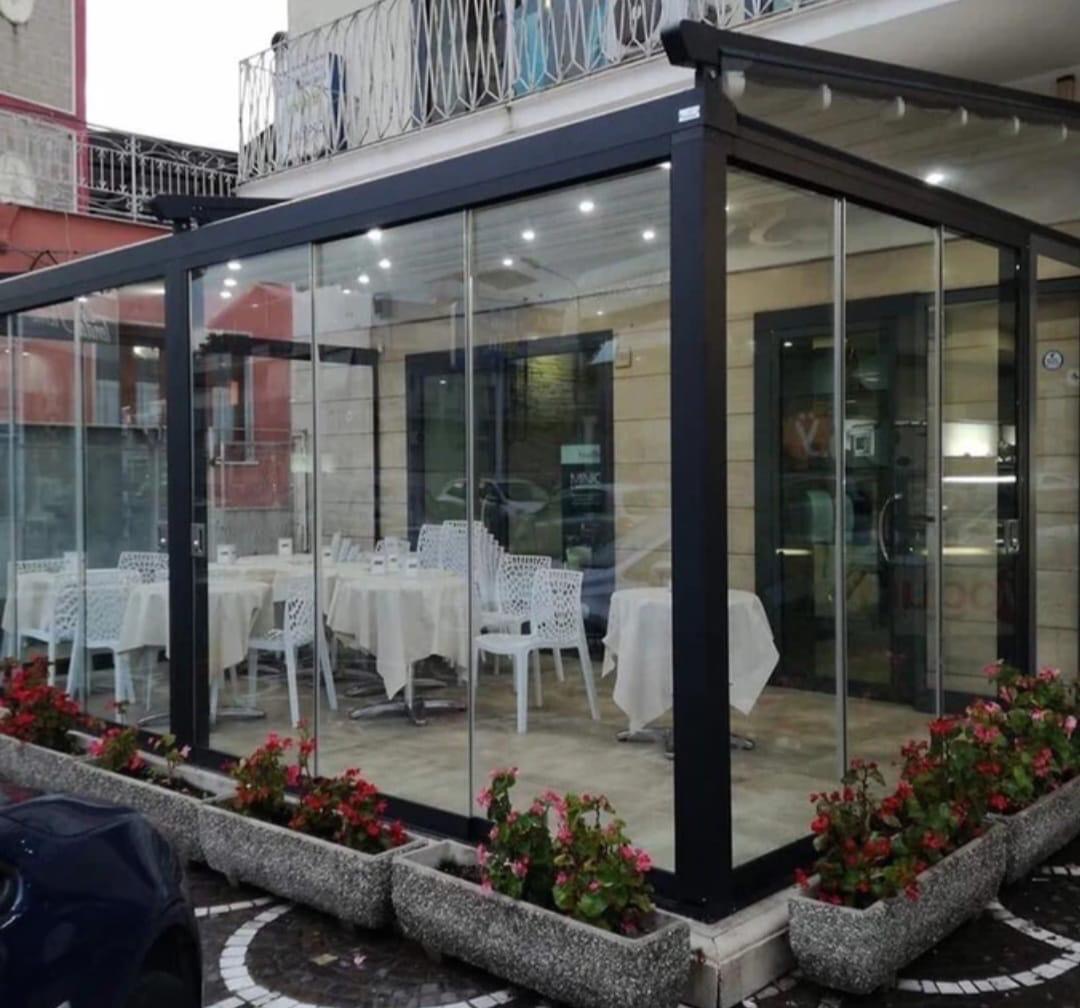 Pergotenda con vetrate nel dehor di un ristorante, con tavoli apparecchiati